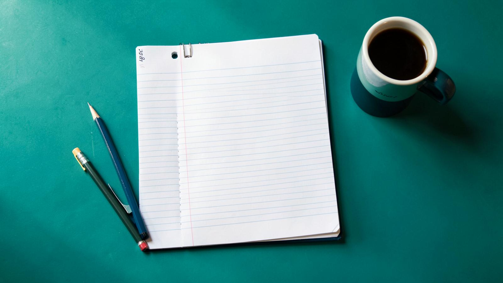 A revision desk with an open notebook, pencils and coffee
